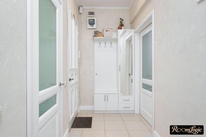 A white small closet in the entryway with open hangers, bench, and mirror