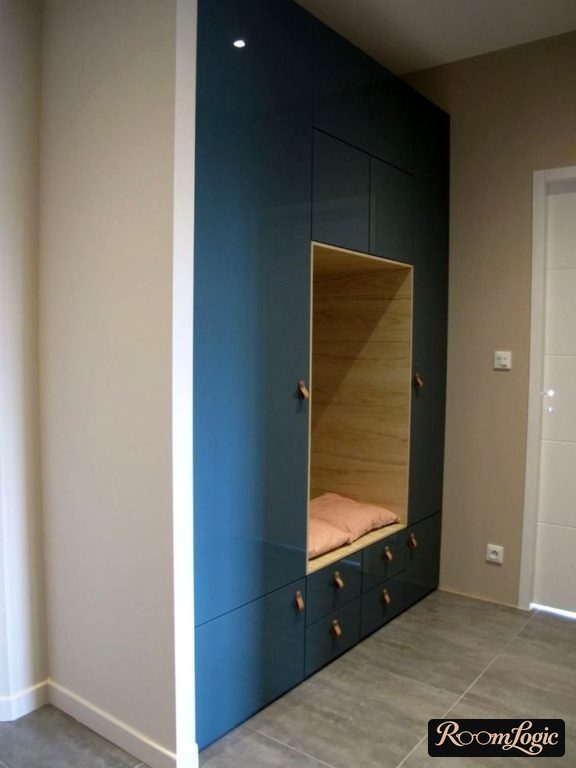 an ordered blue closet from floor to ceiling in the entryway with an open section for sitting