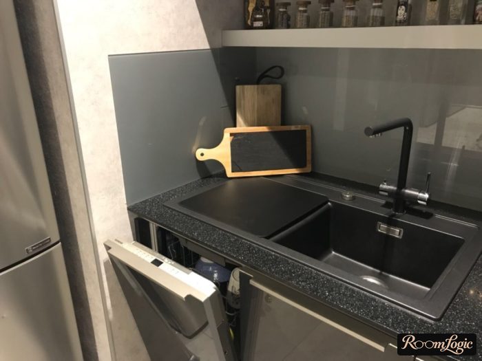 backsplash of glass extending perpendicularly to the wall near the sink