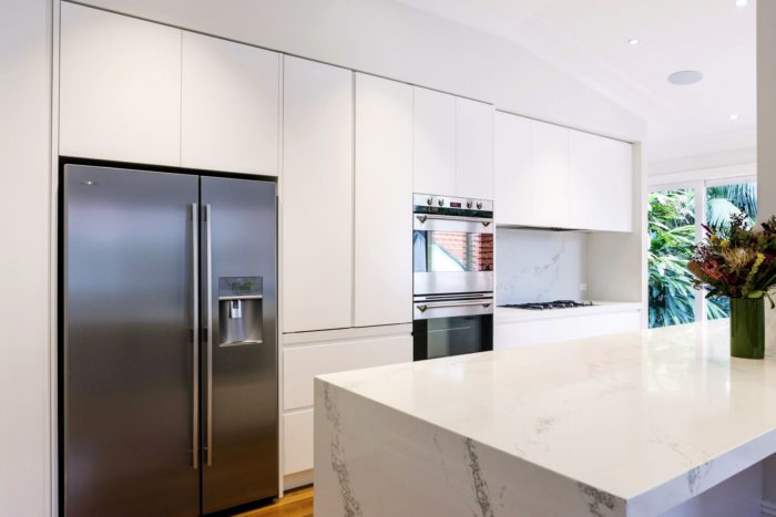 design of a white kitchen in minimalist style with a marble island