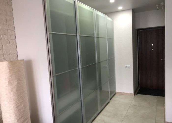 glass sliding-door wardrobe in entryway of one-bedroom apartment
