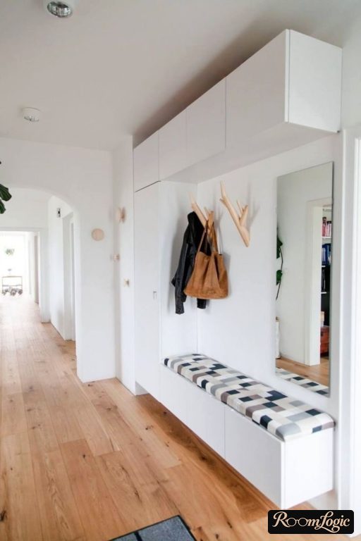 narrow entryway in a hallway with a bench, mirror, and attic storage
