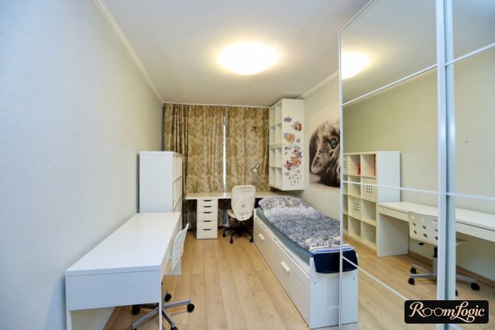 narrow teenager girl room with a workspace by the window and a bed with drawers