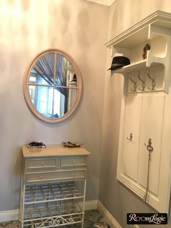 Open hooks, shoe shelves, and an oval mirror in the small entryway