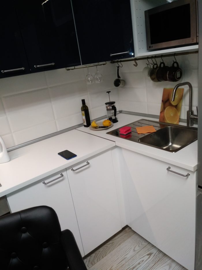 small white kitchen with sink in the corner