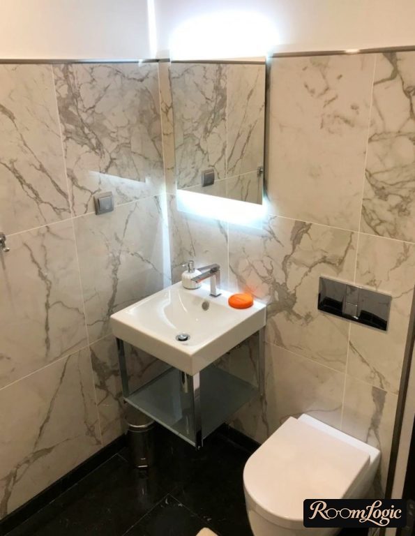 toilet with marble-look tile to mid-wall