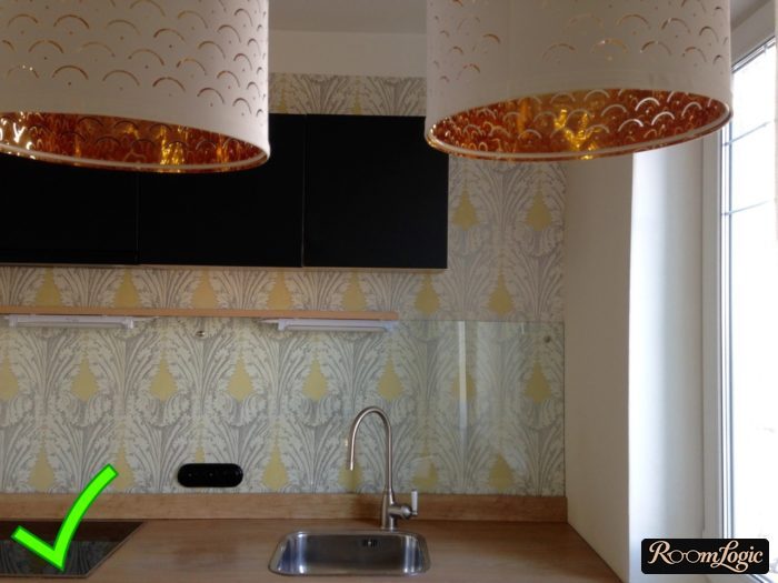 Wallpaper with a gray-yellow pattern behind glass on the kitchen backsplash