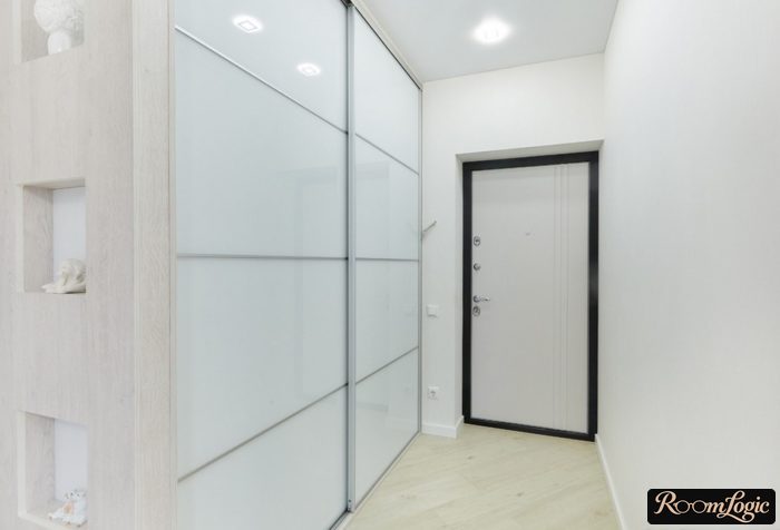 White sliding-door wardrobe from floor to ceiling in small entryway