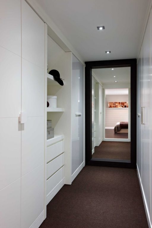 White wardrobe and mirror in narrow hallway